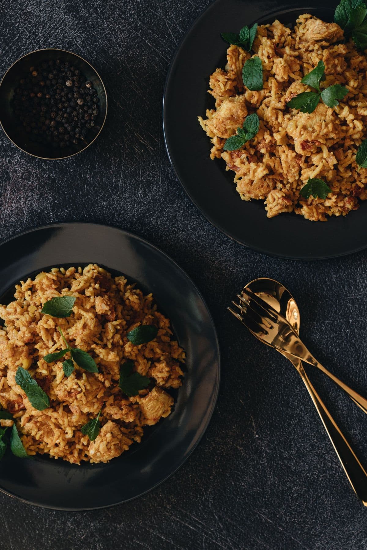 Chicken biryani garnished with fresh mint on a dark plate